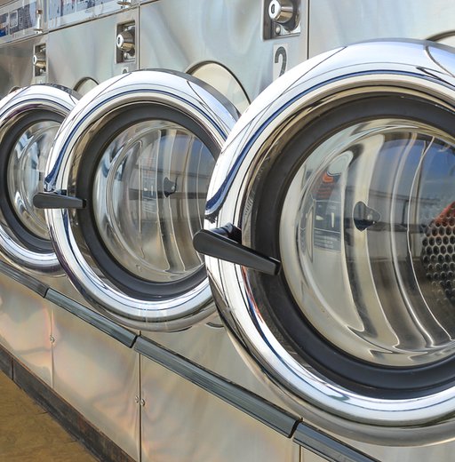 Row of industrial laundry machines in laundromat.